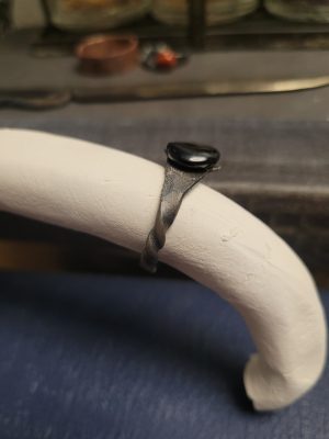 A handmade ring forged from an old nail. It is set with an obsidian stone that absorbs light