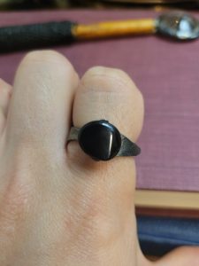 A handmade ring forged from an old nail. It is set with an obsidian stone that absorbs light