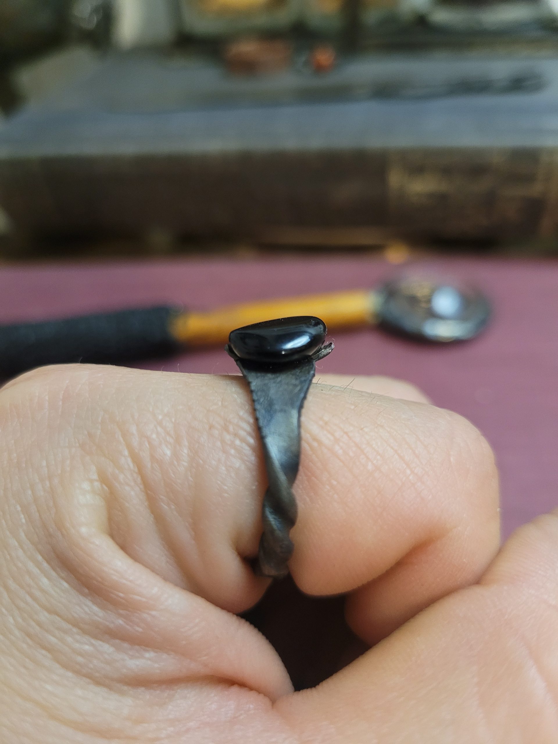 A handmade ring forged from an old nail. It is set with an obsidian stone that absorbs light