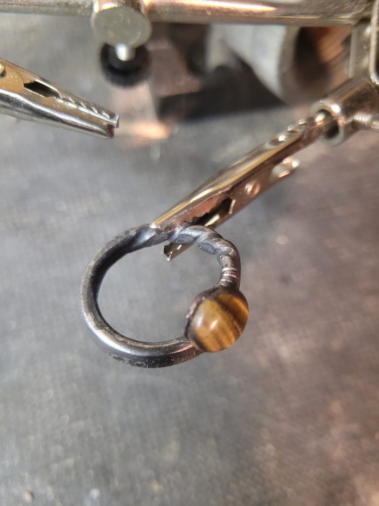 A hand forged ring made from an old nail and set with a polished tiger's eye gemstone. Part of our hand made jewelry collection.