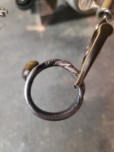 A hand forged ring made from an old nail and set with a polished tiger's eye gemstone. Part of our hand made jewelry collection.